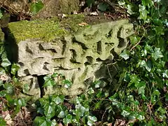 A stone with recessed markings from the ornate footbridge.