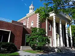 A three-story brick building with a cupola on top on a sunny summer day