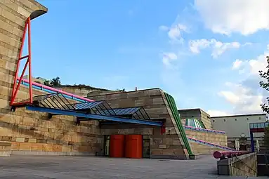 Contradiction (in this case, the mix between monumental curving forms, columns, bossages, but also other Classical elements, and High-Tech glazing, with highly saturated colours) – Neue Staatsgalerie, Stuttgart, Germany, by James Stirling (1984)