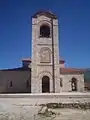 The bell tower on the side of the church. An icon above the entrance depicts Saint Clement and Saint Panteleimon