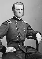 Black and white photo of a clean-shaven man with mutton-chop sideburns. He wears a dark military uniform with two rows of buttons and the one-star shoulder tab of a brigadier general.