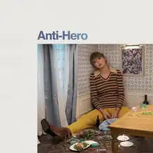 Cover art of Anti Hero, shows Swift sitting in a corner of a tiny house.