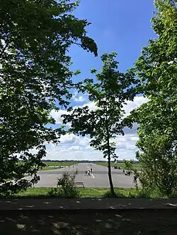 Runway being used as a park, viewed through trees