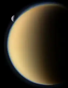 Tethys as it moves pass behind the atmospheric halo of Titan. Tethys is actually not entering Titan's atmosphere as the two are 1,200,000 kilometres or 750,000 miles from each other in this image. Imaged on November 26, 2011,  by the Cassini spacecraft.