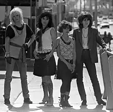 Four women standing next to each other in a street