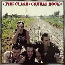 Surrounded by a silver border, a picture of the band members along a single railroad track; Joe Strummer is seen covering one of his eyes. The band name and album title are written in red, with stars on either side of the text.