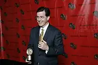 Colbert holding a Peabody Award and giving a thumbs up