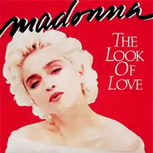 Madonna looks towards the front and tilts her head to the right. She is wearing a white dress, with bare shoulders.