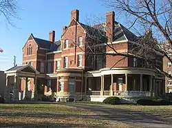 A brown multi-story building on a green field.