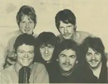 Six smiling men are shown in a close-up shot.