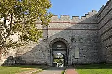 Photograph of a stone city gate, with a large arched entrance