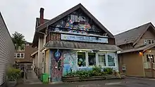 Photograph of a building's exterior, which is covered in colorful murals and has a sign displaying "The Third Eye Shoppe" in the center