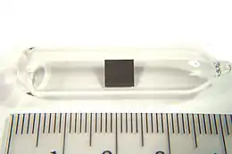 Small (3 cm) ampule with a tiny (5 mm) square of metal in it