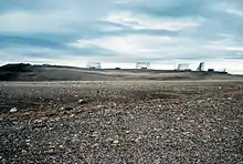 A series of four metal structures silhouetted on the horizon, with a golf ball looking dome to the left