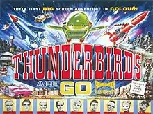 A bold title in the centre of the image reads "Thunderbirds Are Go". A top caption spanning the width of this colourful film poster reads "Their First Big-Screen Adventure In Colour!" Between the title and the caption, three rocket-shaped vehicles – one blue, one green and one red – appear to blast outwards from the poster itself. Other images lining the sides of the poster include an exotic pink car, a snake-like rock creature apparently shooting fire from its mouth and, at the base, portraits of some of the principal cast members, who are marionette puppets.