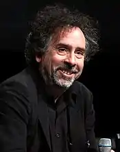 A head shot of a dark-haired, bearded man smiling