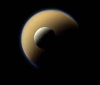 The Saturn-facing side of Titan and Rhea (Saturn's second-largest moon), imaged on July 16, 2011, by the Cassini spacecraft as Rhea passed in front of Titan. Titan's massive atmosphere can be clearly seen as a bluish haze around the yellow moon; while Rhea obviously has no such atmosphere.