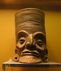 An expressive orange-ware clay vessel in the Toltec style.