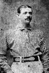 A man standing in his baseball uniform.