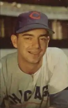 A man wearing a blue baseball cap with a red "C" on the front and a white baseball jersey with "Chicago" written across the chest in blue smiles for the camera.