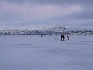 Frozen Torneträsk lake, with people walking and taking pictures on its surface (Jan 2013)