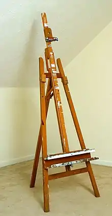 Wooden easel standing in empty room.