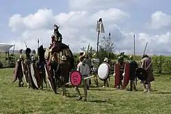 A group of men dressed in clothes and carrying weapons from the 3rd century BC accompanying a medium-sized elephant