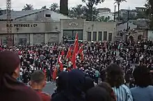 A crowd with some Turkish flags in front of a building