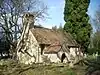 A simple chapel with a bellcote and a protruding porch, and winter trees behind