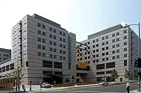 Two white multi-floored squared buildings with blue colored windows. There is a street and clear sky surrounding the buildings.