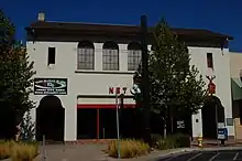 A compact building with white walls, round windows, and a brown roof.