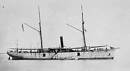 broadside view of a two-masted schooner with a smoke stack in the center, at anchor, without sails, painted white