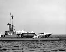 A rocket taking off horizontally from the deck of a surfaced World War II-era submarine