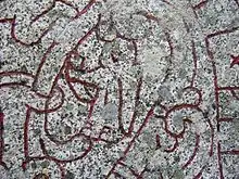 A female figure bearing a horn on runestone U 1163.