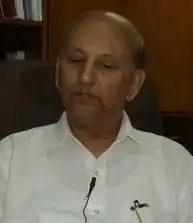 Photograph of a bald man wearing white shirt.