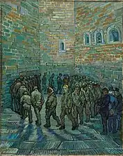 In an indoor prison yard a large group of men walk in a circle, one behind the other. The face of the prisoner in the centre of the painting and looking toward the viewer looks like Van Gogh.