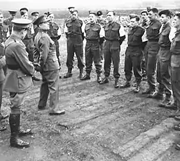 A photograph of a group of officer candidates stood outside in front of two instructors