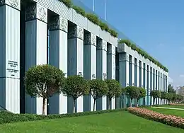 Photo of a building with columns and trees planted along the wall