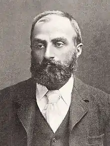 A middle-aged bearded man wearing a tie, waistcoat and jacket.