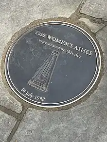 A metal plaque set in flagstones with a pyramid shaped trophy and the date 20 July 1998.