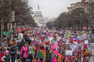 Pennsylvania Ave., completely packed with protesters, mostly women, many wearing pink and holding signs with progressive feminist slogans