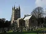 Stone building with square tower. In the foreground are gravestones.