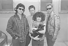 The band standing, with Exene holding a cat