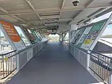 A footbridge with a roof covering it and advertisements on the walls