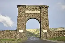 A large arch made of irregular-shaped natural stone over a road