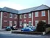 red brick building with small car park in front.