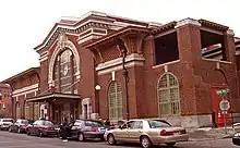 A red-brick train station, with cars in front