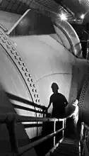 A worker stands by the 30 ft (9.1 m) diameter Nevada penstock before its junction with another penstock that delivers water to a turbine.